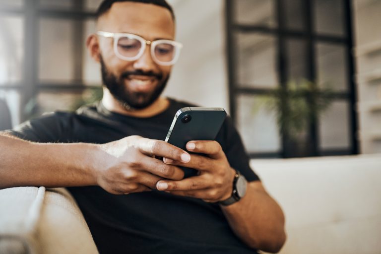 Happy man, social media phone and living room relax, typing smartphone and online communication, reading notification and web on sofa